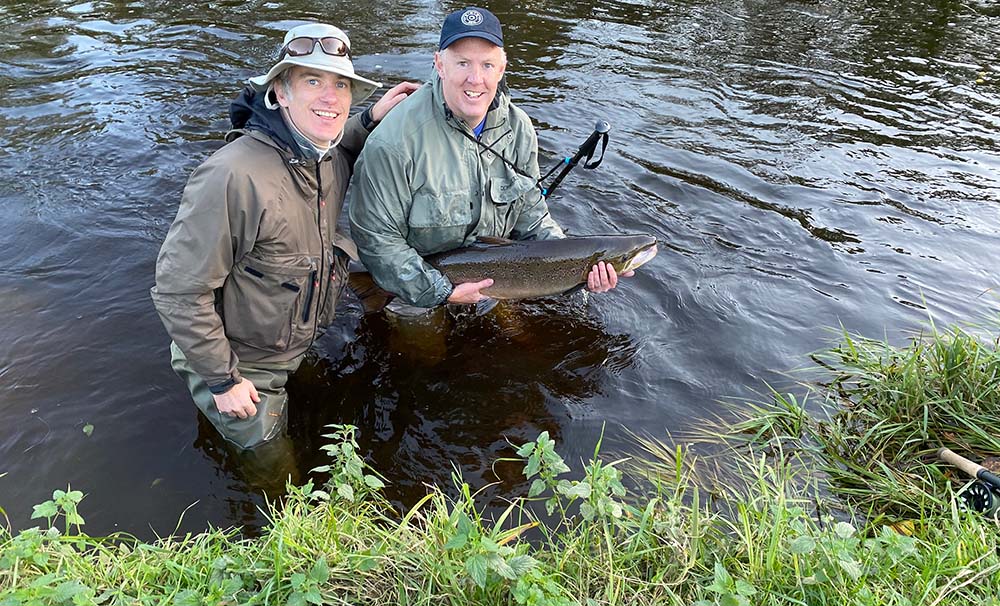 happy guided salmon fishing client on river tweed with 34lb salmon